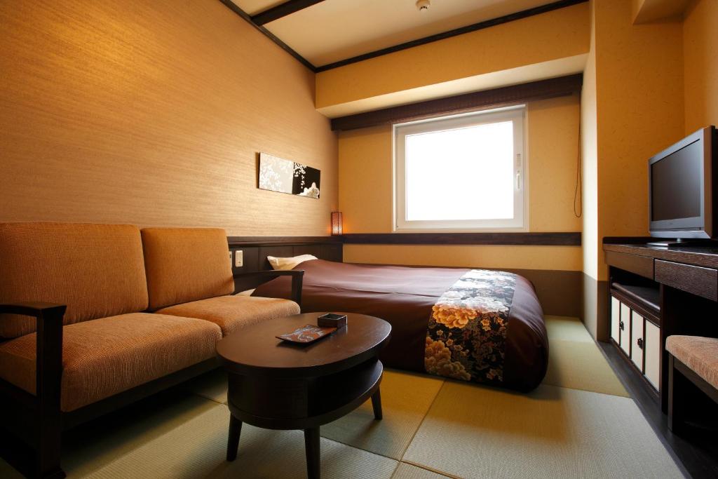 a hotel room with a bed and a couch and a tv at Takayama Ouan in Takayama