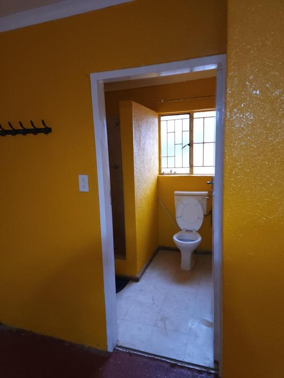 a bathroom with a toilet in a yellow wall at WAMPEX GUEST HOUSE IN NORTHAM CBD 239 COAL STREET in Northam