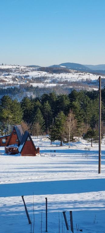 a snow covered field with a red barn in the distance at A Pine vikendica u srcu Zapadne Srbije in Nova Varoš