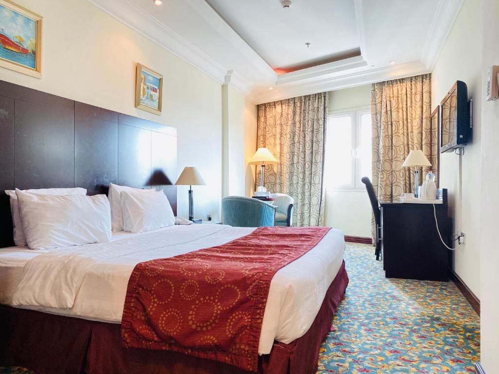 a hotel room with a large bed with a red blanket at Musherib Hotel in Doha