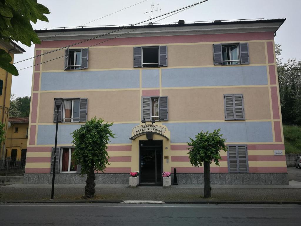 un edificio colorido con una puerta y dos árboles delante en ALBERGO DELLA STAZIONE, en Cairo Montenotte