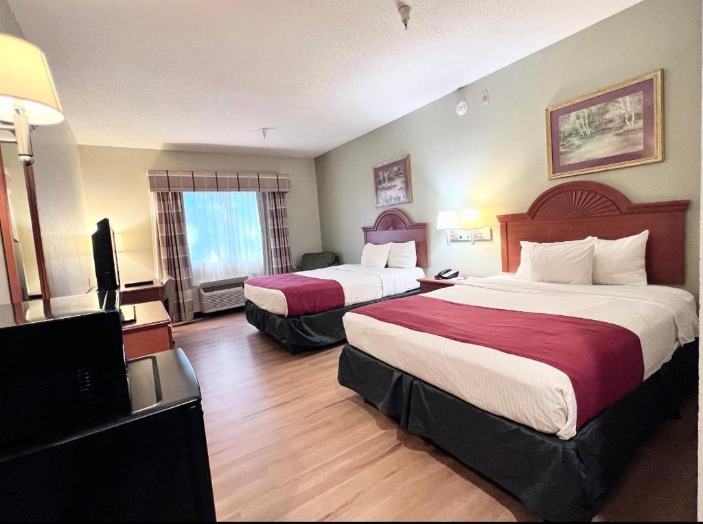 a hotel room with two beds and a flat screen tv at Americas Best Value Inn Wiggins in Wiggins