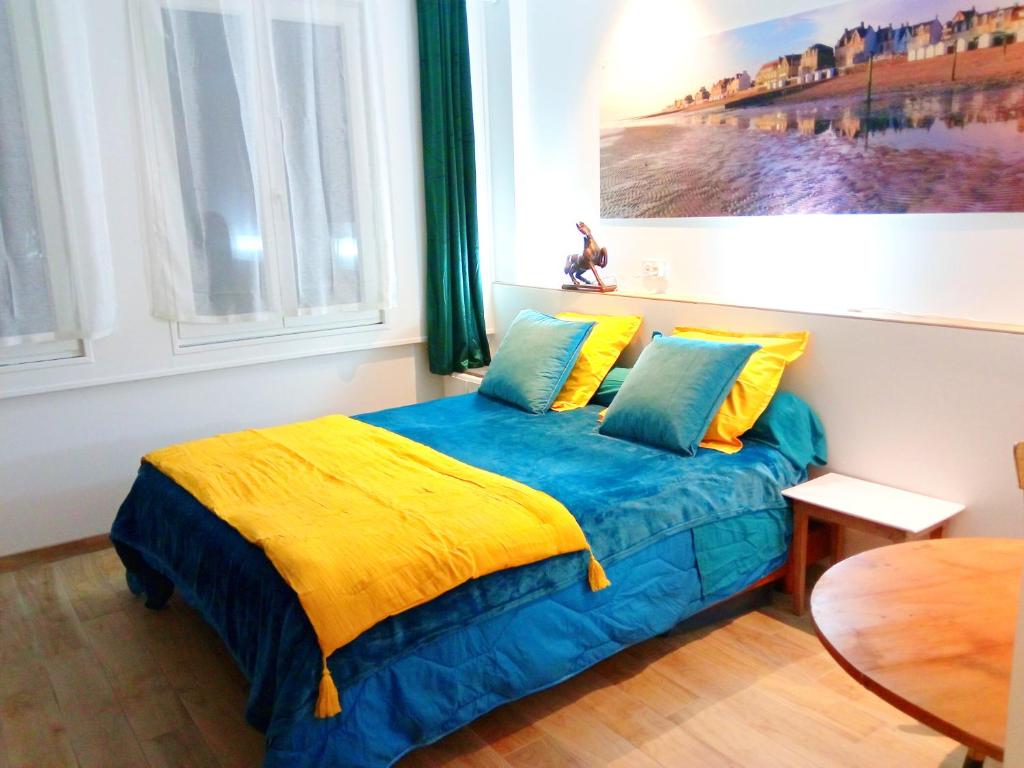 ein Schlafzimmer mit einem Bett mit einer gelben und blauen Decke in der Unterkunft MYSaintAubin in Saint-Aubin-sur-Mer