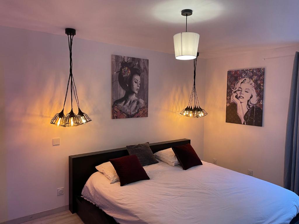 Domaine de Maeva في رومان-سور-إيزير: غرفة نوم بسرير بثلاث صور على الحائط