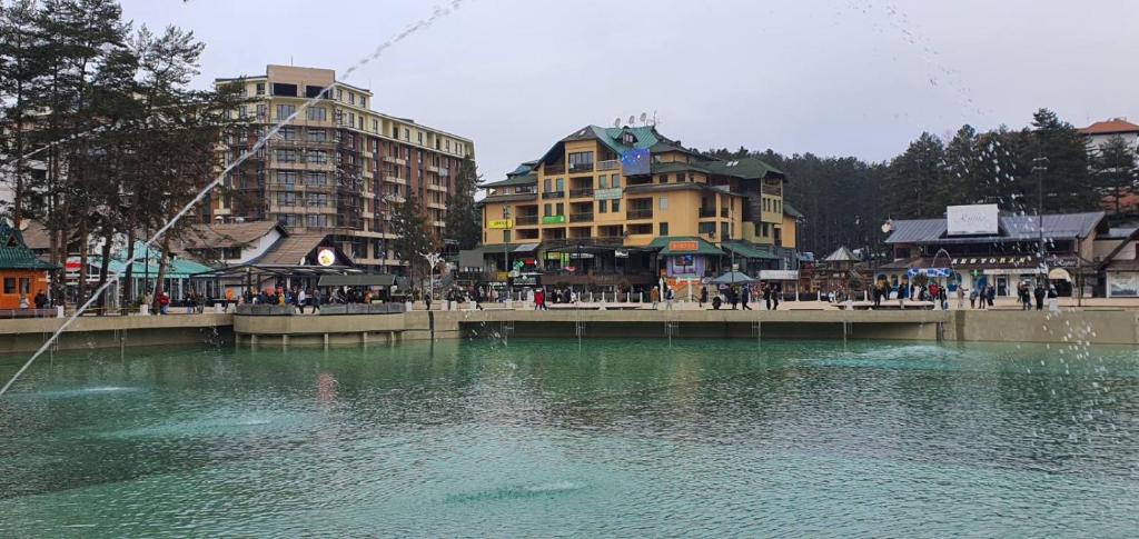 兹拉蒂博尔Apartman Trg Vila Jezero Zlatibor的一大片水体,有建筑背景