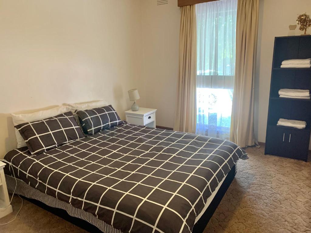 a bedroom with a bed with a black and white checkered blanket at Golden House in Springvale