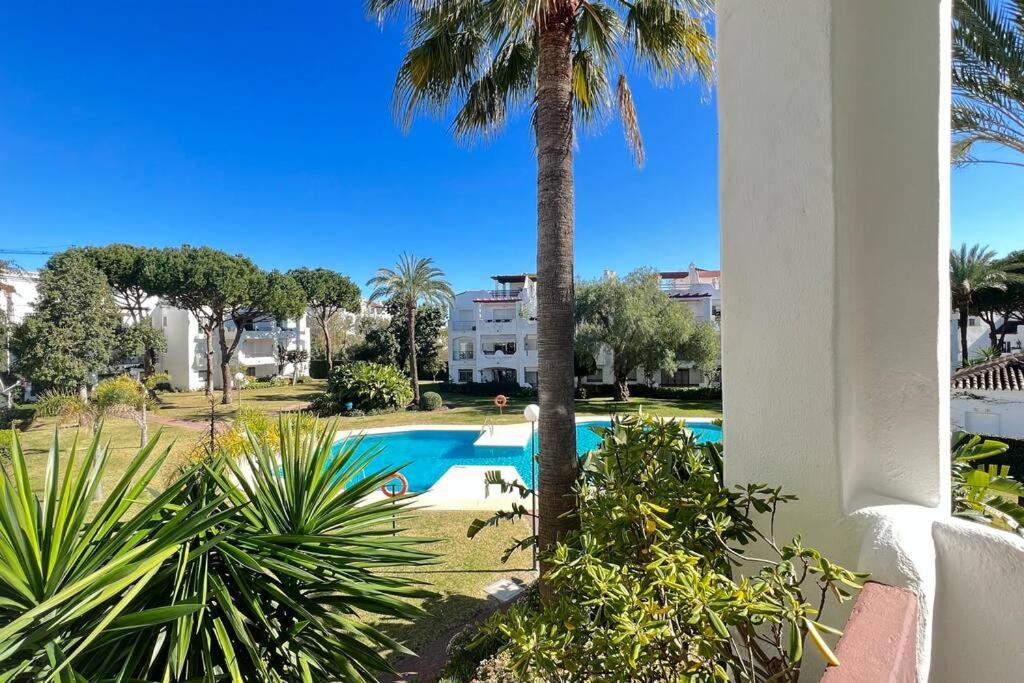 basen z palmą obok budynku w obiekcie Costalita - 2 bedroom apartment 350m from the beach w mieście Estepona