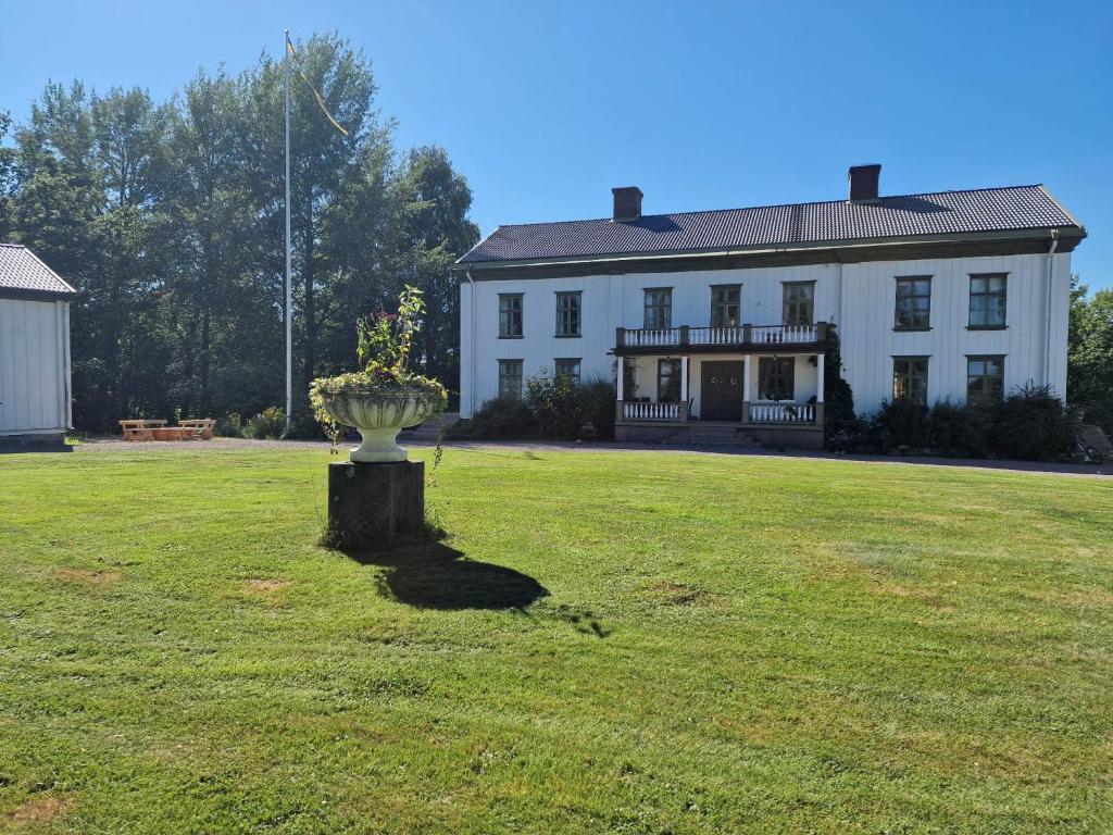 una gran casa blanca con un jarrón en el patio en Alstrums gård en Killstad