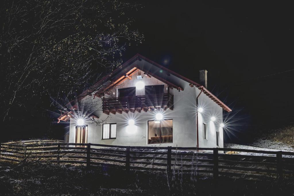 a house with lights on the side of it at night at Cabana Stânceni in Drăgoiasa