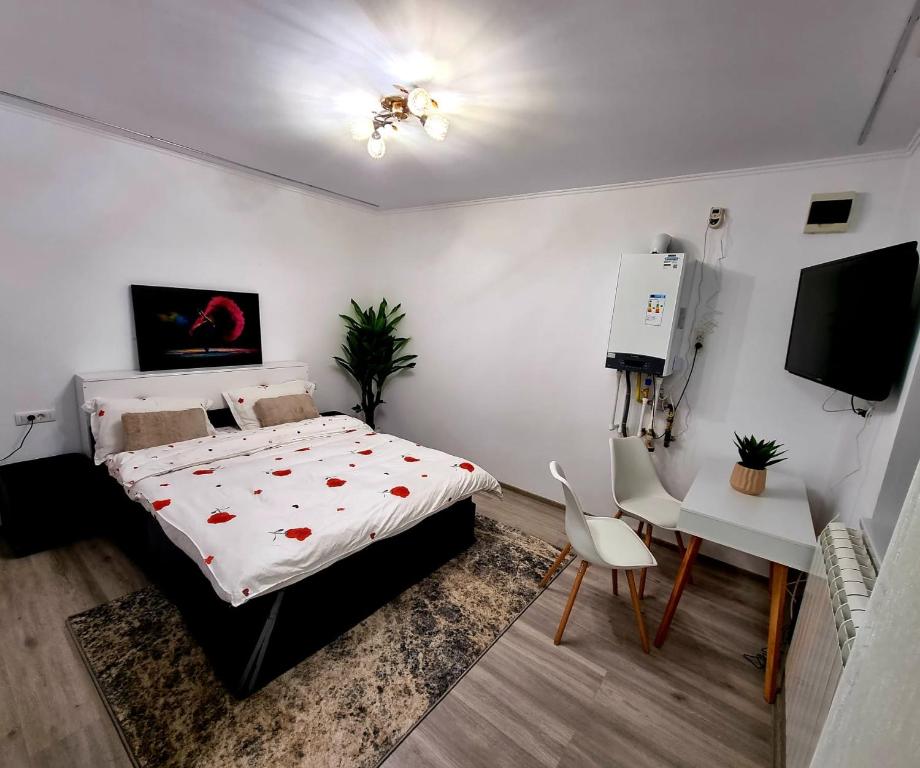 a bedroom with a bed and a table and a tv at Camera/garsoniera in regim hotelier in Comăneşti