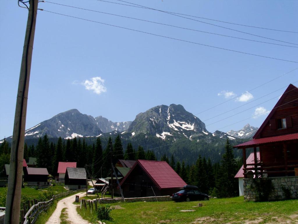 a dirt road in a village with mountains in the background at Apartment Vujisic in Žabljak