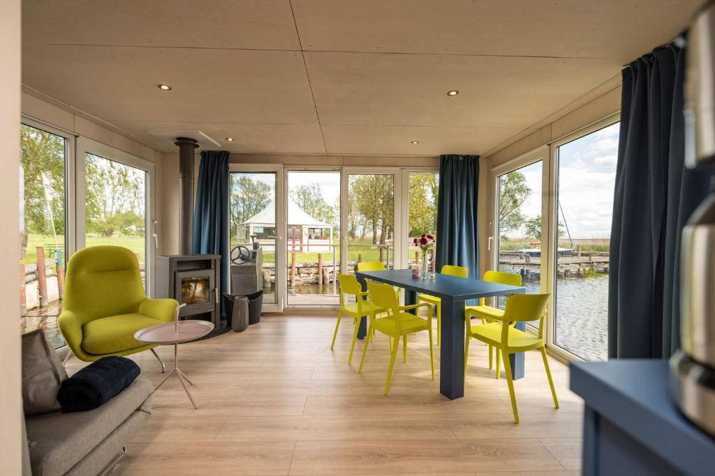 a living room with a table and yellow chairs at Hafenresort Karnin _ Hausboot Selma in Karnin