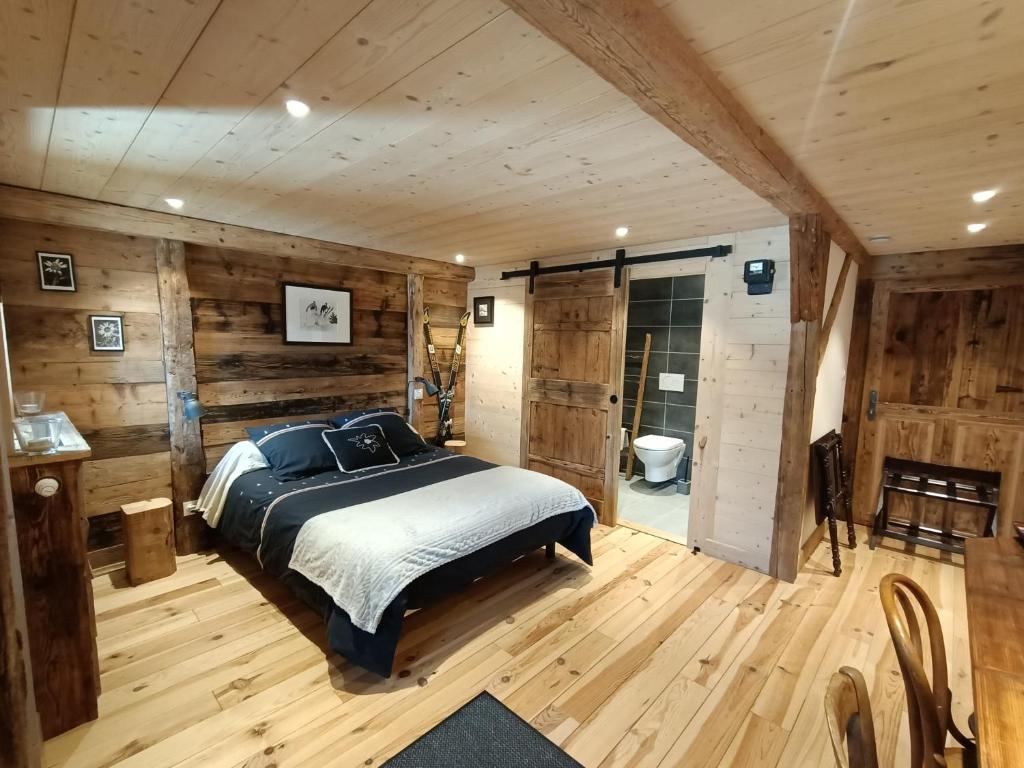 una camera con un letto in una stanza con pareti in legno di Atelier des Sapins Blancs (chambre double) a Vacheresse