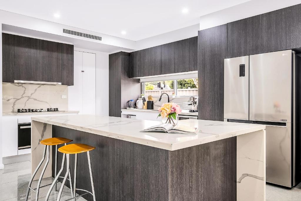a kitchen with a large island with two stools at Blue Haven Retreat - Beverly Hills 208 in Sydney