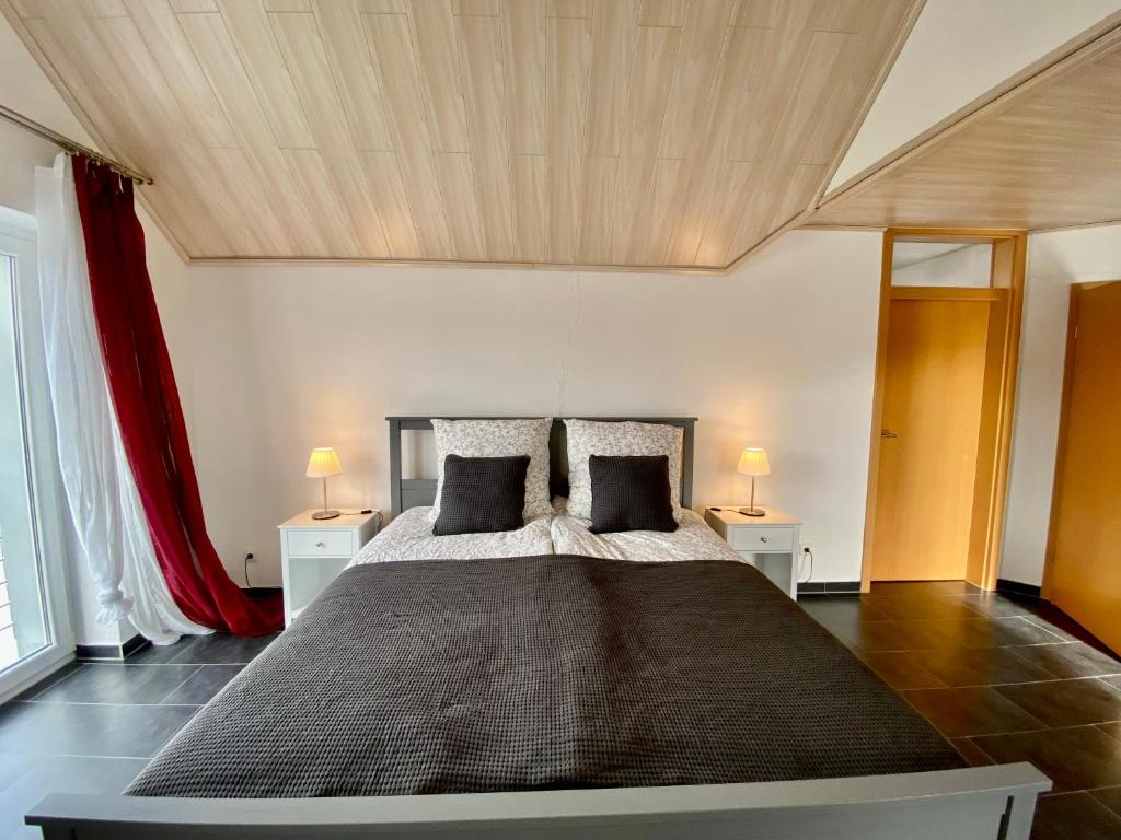 a bedroom with a large bed with two tables and two lamps at Moderne Ferienwohnung Seeblick in Freudenberg