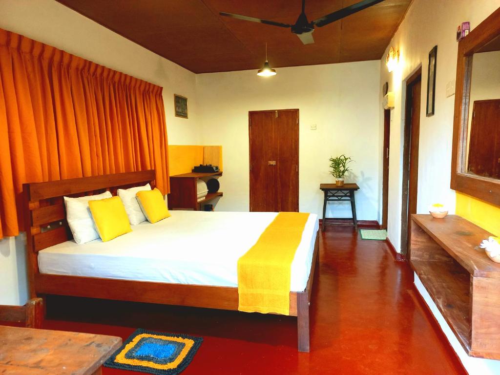 a bedroom with a large bed with yellow pillows at Coco Garden Villas 1 in Hikkaduwa