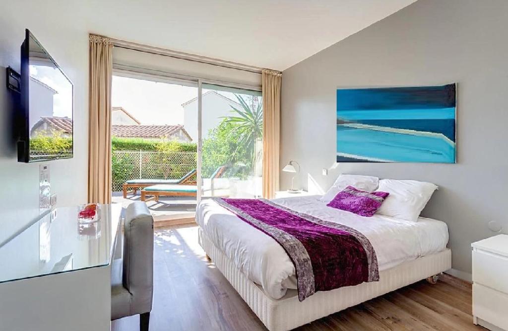 a bedroom with a bed and a large window at Hotel Sable Et Soleil - Port, Plage et spa in Fréjus