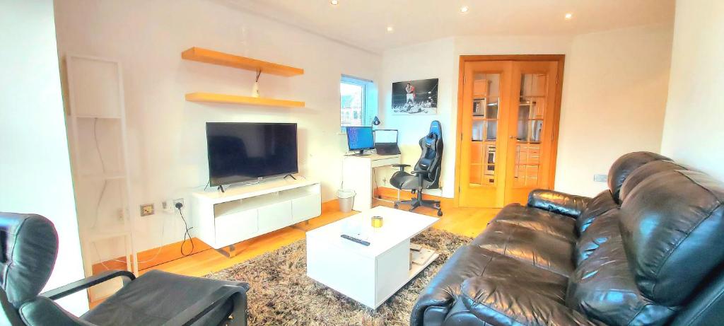 uma sala de estar com um sofá de couro e uma televisão de ecrã plano em Cosy 2 bedroom appartment with gated parking by River Thames em Kingston upon Thames