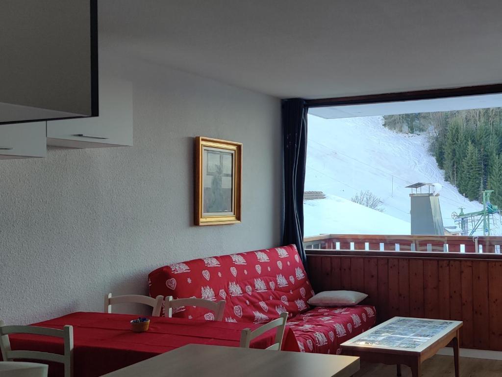 a living room with a red couch and a window at Les Brasses in Viuz-en-Sallaz