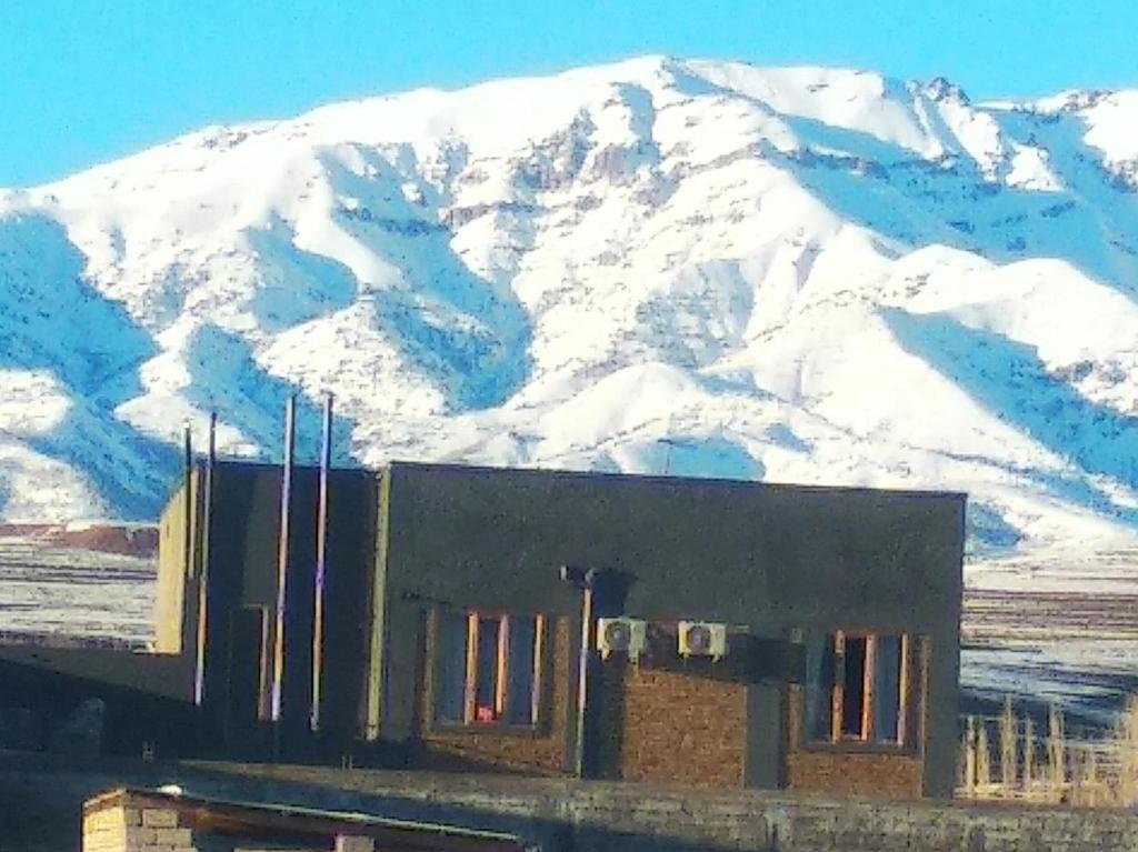 a building with a snow covered mountain in the background at Дом для отпуска "Samira" in Chimbaylyk