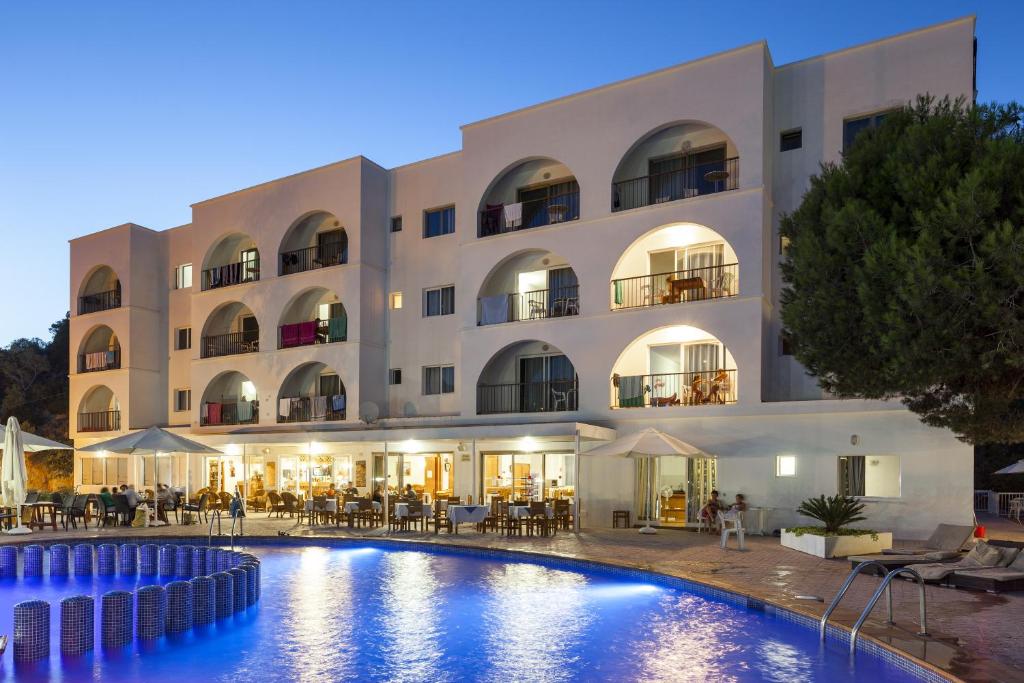 un hotel con piscina frente a un edificio en Aparthotel Puerto Cala Vadella en Cala Vadella