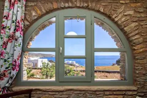an arched window with a view of the ocean at m.houses 2 in Agios Romanos