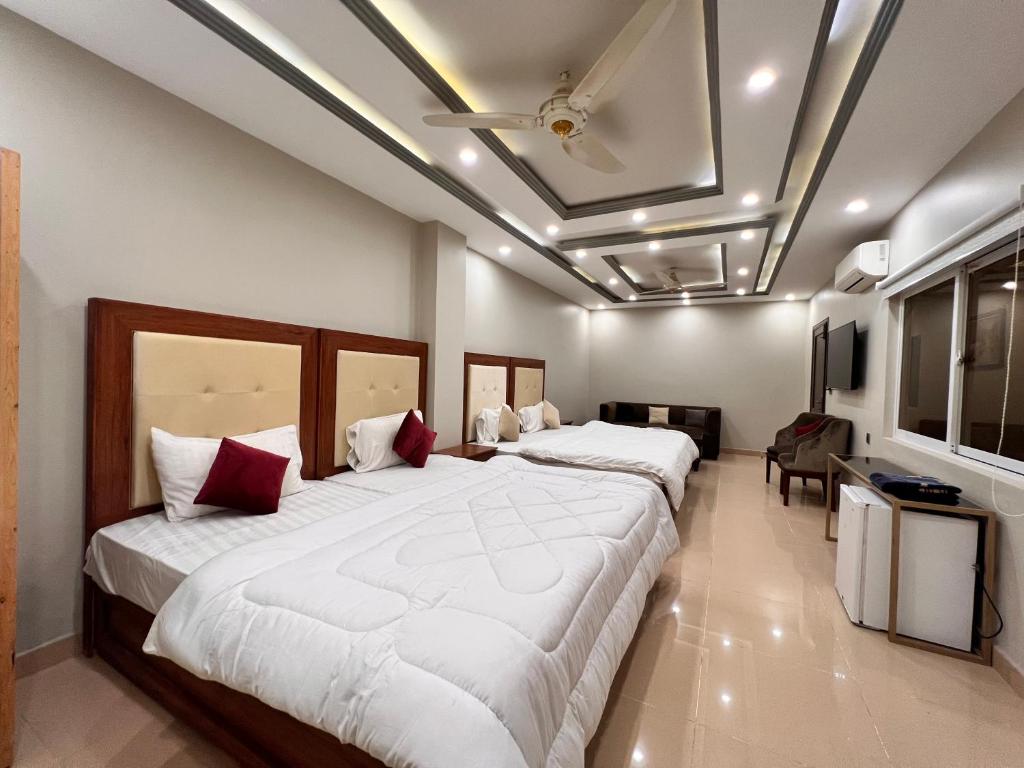 ein Schlafzimmer mit 2 Betten und einem TV in der Unterkunft Grand Luxury Hotel Multan in Multan