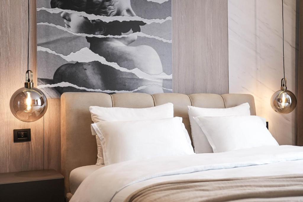 a bedroom with a bed with white pillows and a painting at ZEST Residence in Kragujevac