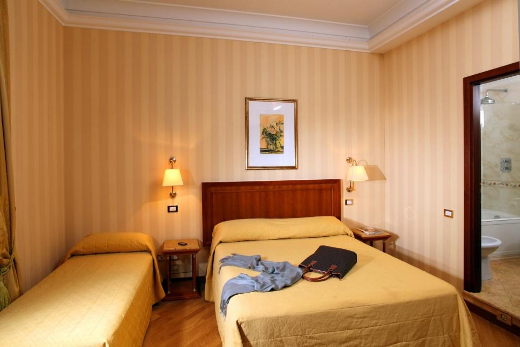 ローマにあるPiave and Flavia apartmentsのベッド2台とバスタブ付きのホテルルームです。