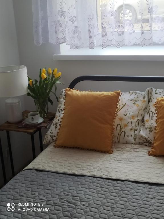 uma cama com uma almofada e um vaso de flores em Apartament Miodownik em Międzylesie