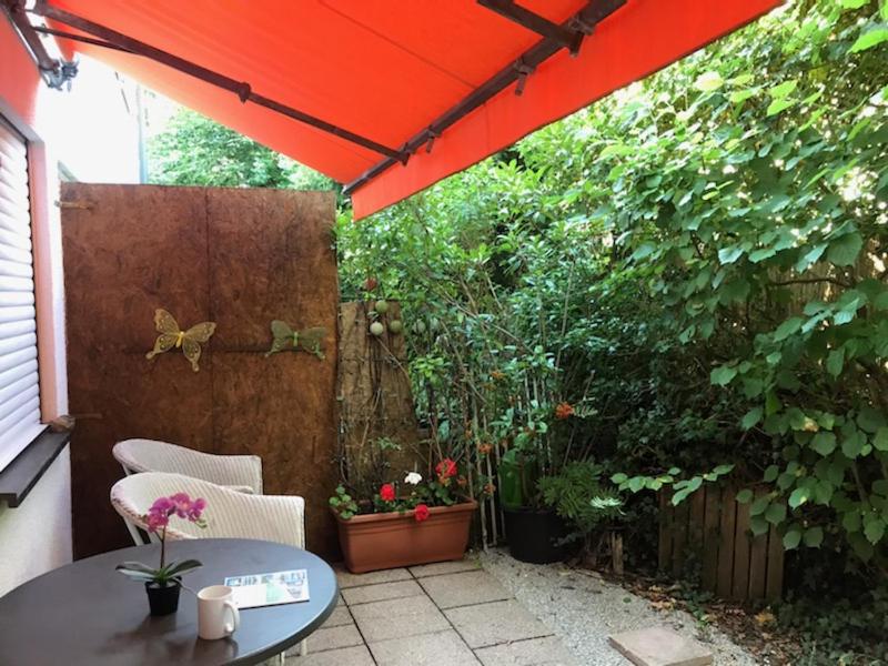 d'une terrasse avec une table et un parasol rouge. dans l'établissement Wo München am schönsten ist, à Grünwald