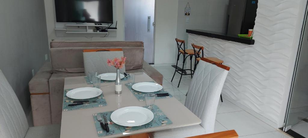ein Esstisch mit weißen Tellern und Blumen darauf in der Unterkunft Caribean's house in Arraial do Cabo
