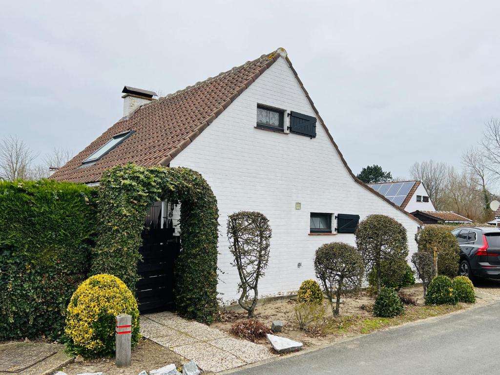 a white house with ivy growing around the doorway at Vissershuisje 6 te Koksijde in Koksijde