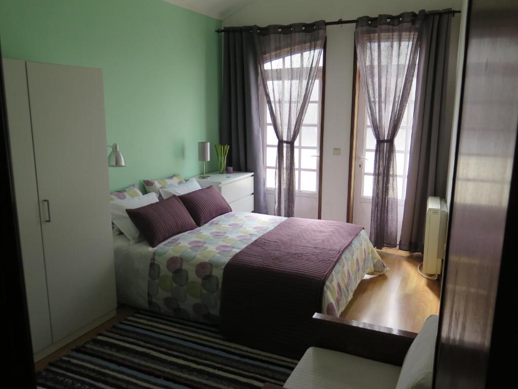 a bedroom with a bed and two large windows at Aveiro Luz in Aveiro