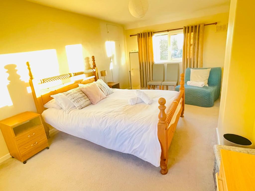 a bedroom with a large bed and a chair at St Ives, King Bed Cosy home, parking, fast Wi Fi in St Ives