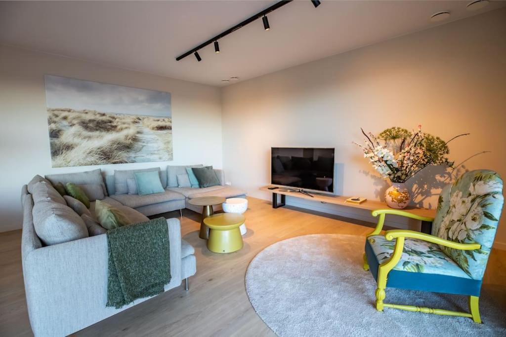 een woonkamer met een bank en een tv bij Sunny Terras, Cozy in the dunes in Cadzand