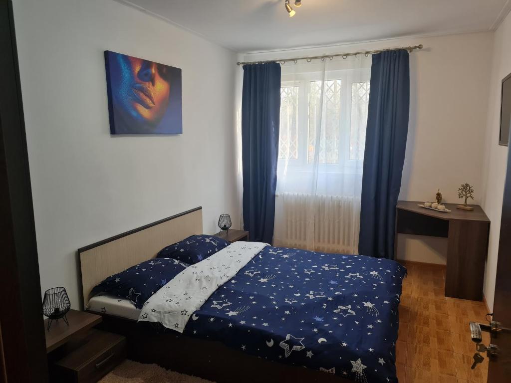 a bedroom with a bed with a blue comforter and a window at Two Rooms Parc Ior Apartament in Bucharest
