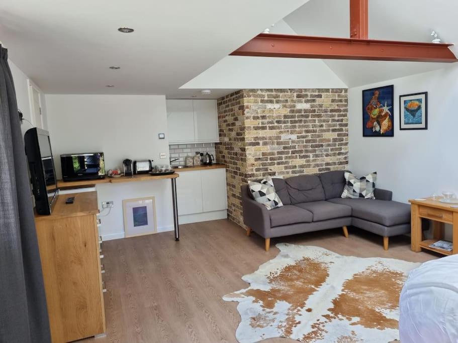 a living room with a couch and a brick wall at Garden Lodge close to Wakehurst and Kew Seed Bank Ardingly in Ardingly