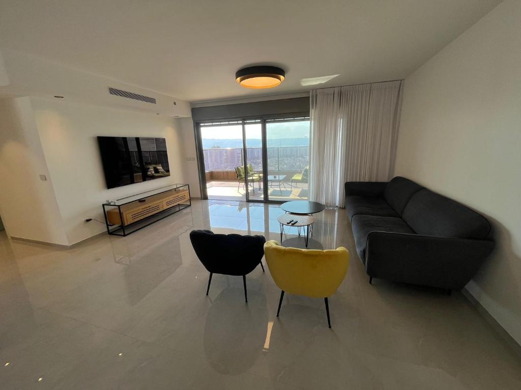 a living room with a couch and chairs and a television at luxury condo in Qiryat Motzkin