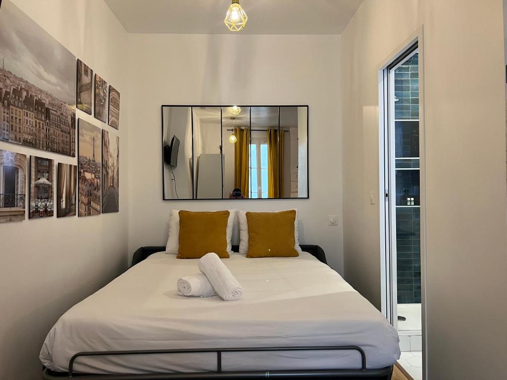 a bedroom with a bed with two pillows and a mirror at EXPOSITION APPARTEMENT in Paris