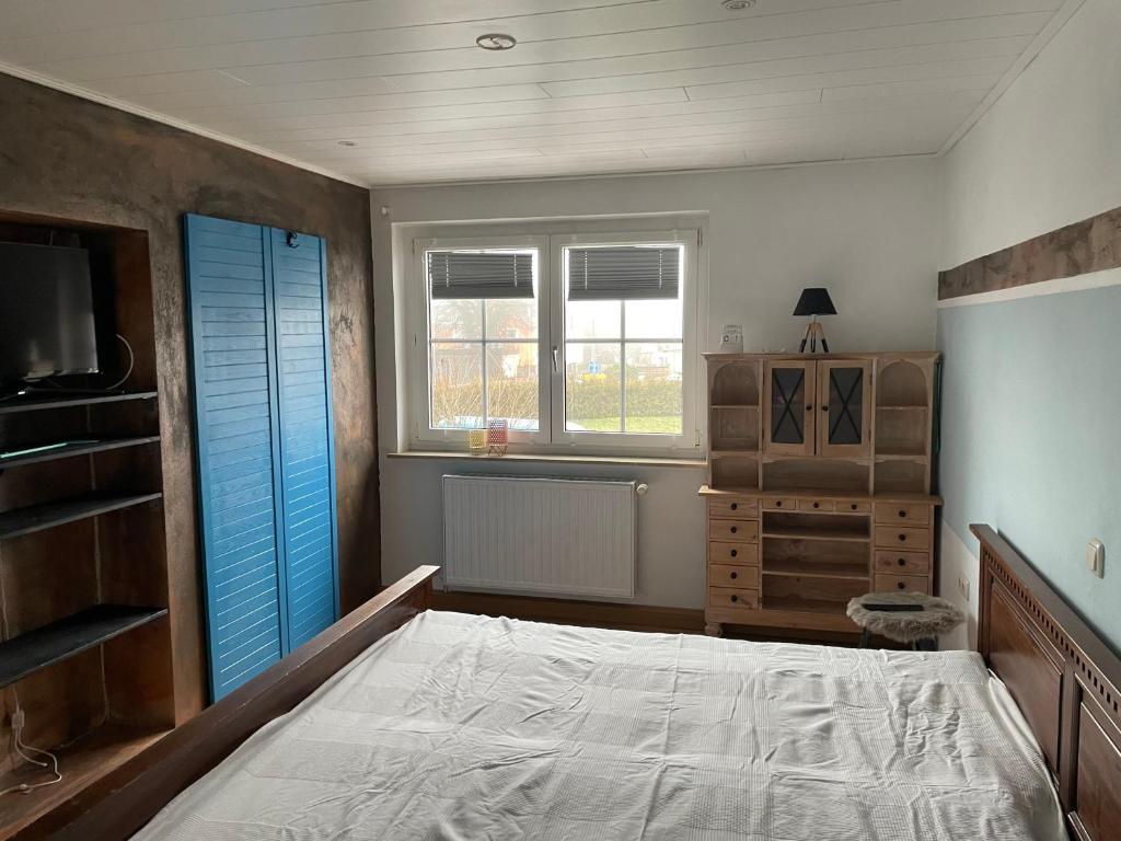 Schlafzimmer mit einem Bett, einer Kommode und Fenstern in der Unterkunft Ferienwohnung in Gattendorf