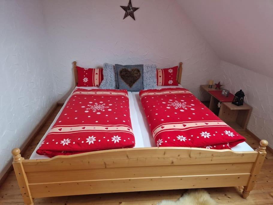 a bed with two red pillows on it at Ferienwohnung am Steinwald 
