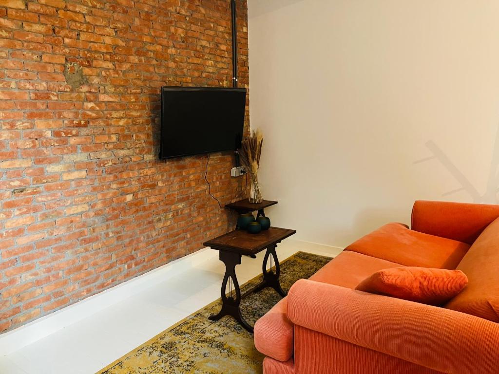 a living room with a couch and a tv on a brick wall at BnB Suikernest in Antwerp