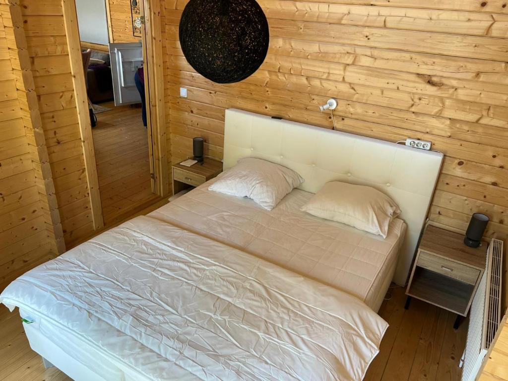 ein Schlafzimmer mit einem weißen Bett an einer Holzwand in der Unterkunft Villa Bartje in Schoonebeek