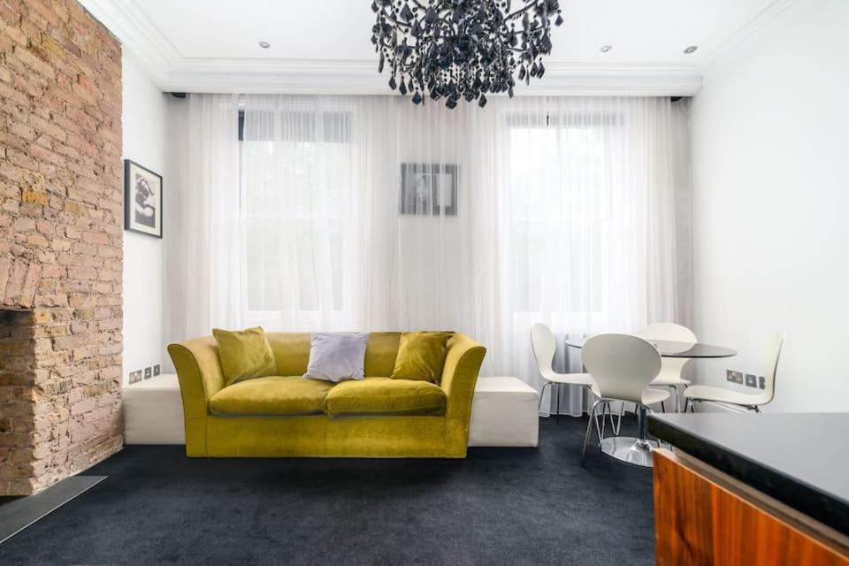 een woonkamer met een gele bank en een tafel bij Award-winning designer apartment in Londen