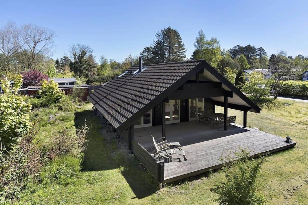 uma pequena casa com um deque num campo em Hyggeligt og lyst feriehus nær stranden i Klint em Nykobing Sjaelland