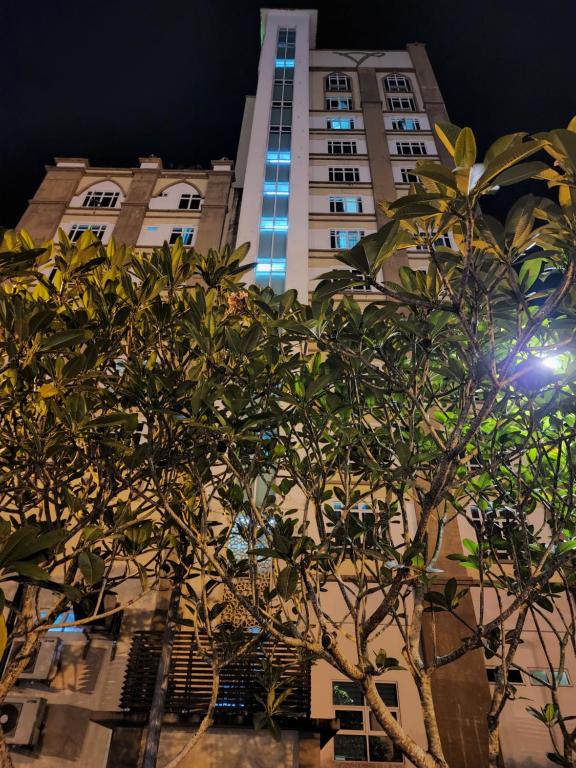 un edificio alto con un árbol delante de él en The Viana Apartment 2, en Kota Bharu