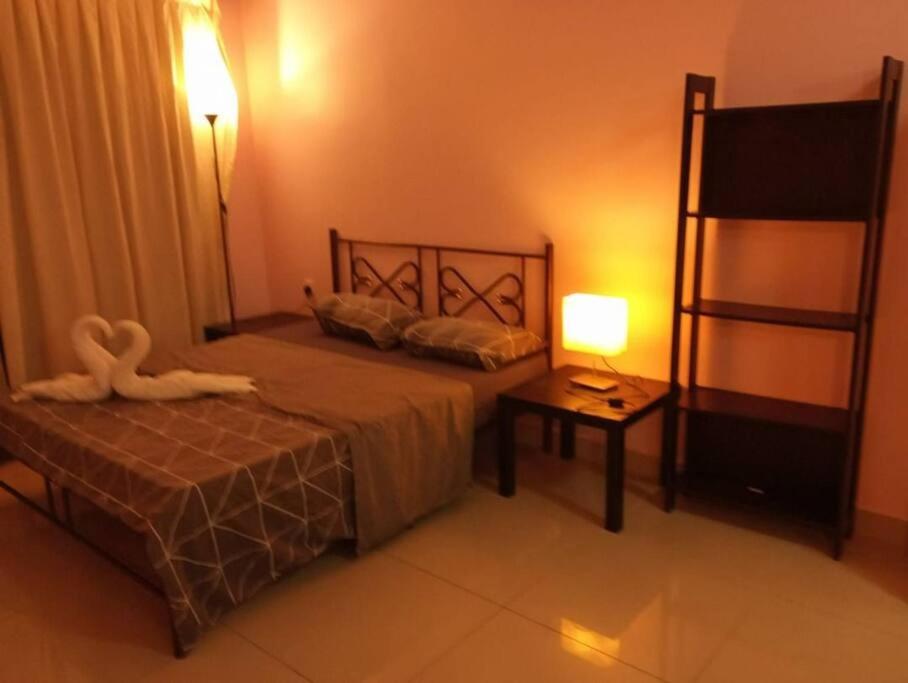ein Schlafzimmer mit einem Bett und einem Tisch mit einer Lampe in der Unterkunft HB1506-Cyberjaya-Netflix-Wifi-Parking,3049, 3049 in Cyberjaya