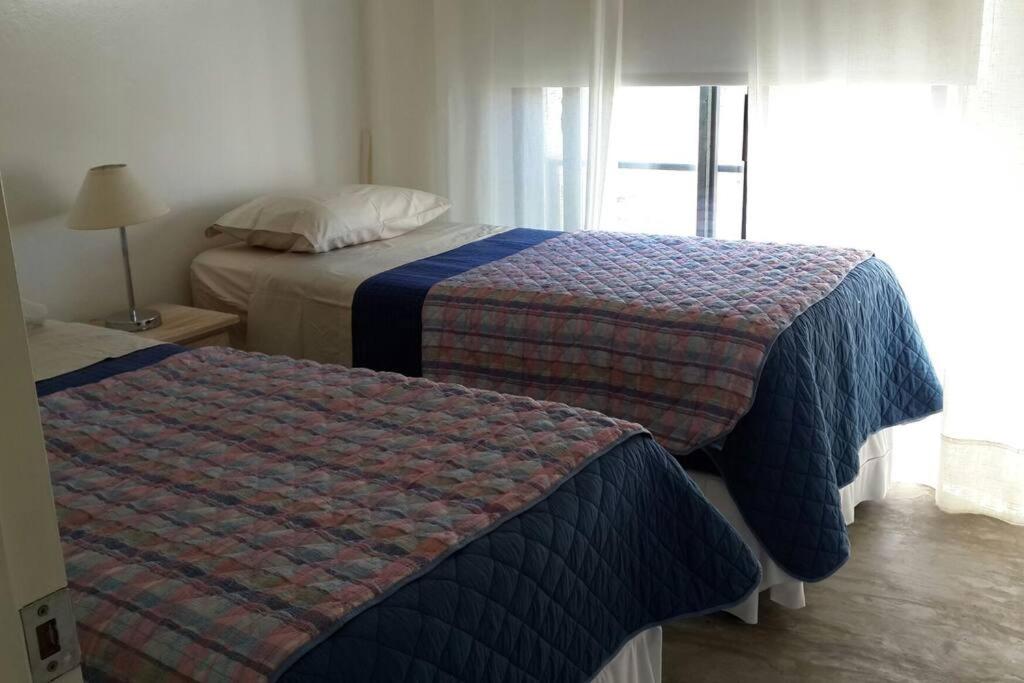 2 camas en una habitación de hotel con ventana en Casa Ambar, vista al mar, Punta del Diablo,Uruguay, en Punta del Diablo