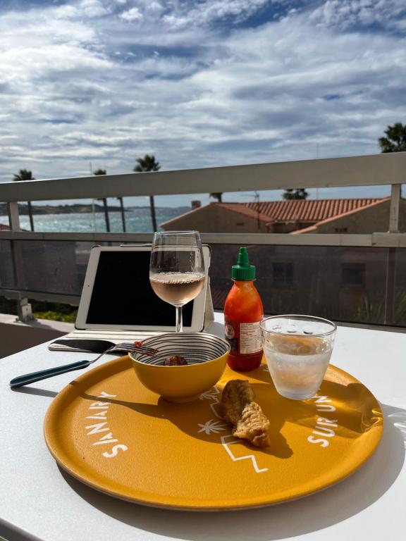 une assiette jaune avec un verre de vin et un bol de nourriture dans l'établissement Sanary View - Un écrin sur la Mer, à Six-Fours-les-Plages